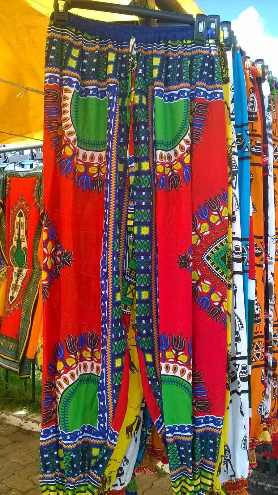 Pantalons en imprimés africains colorés suspendus sur un étal du Maasai Market au Kenya