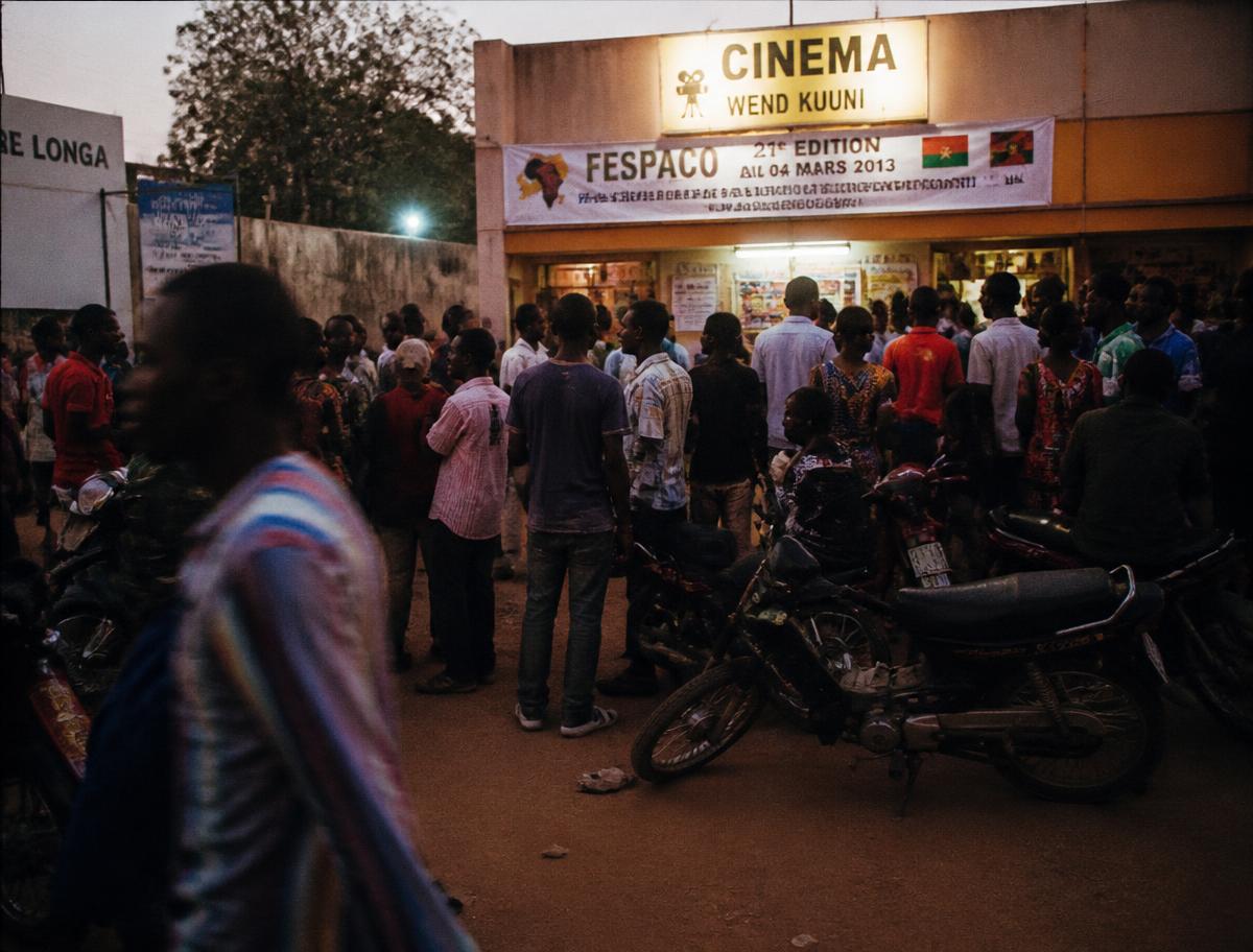 Foule de festivaliers devant une salle de cinéma à Ouagadougou au crépuscule