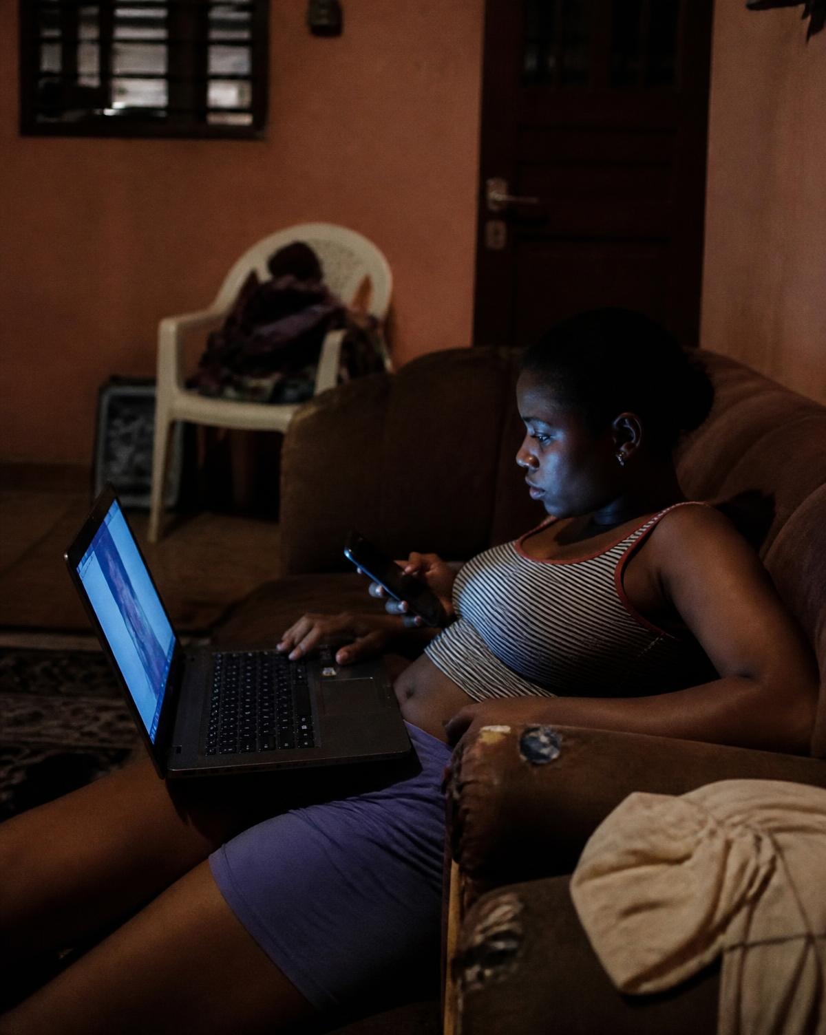 Trois jeunes adultes regardent un film sur un ordinateur portable dans un salon la nuit